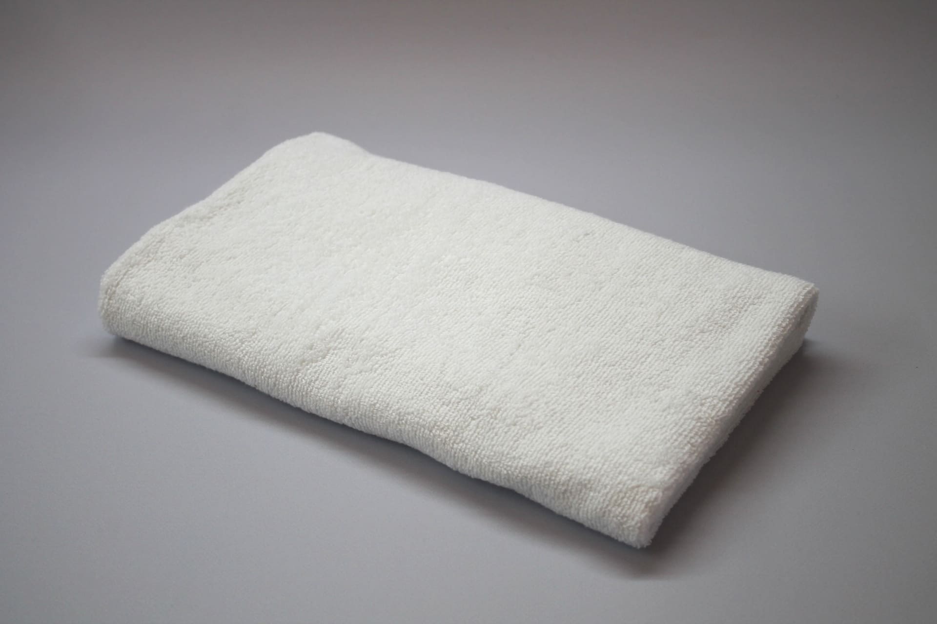 Окпд полотенце махровое. Белое махровое полотенце сложено углом.